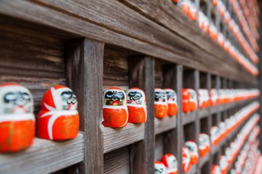 Japonya 'nın Minoh, Osaka kentindeki Katsuo-ji tapınağındaki tahta duvarda küçük daruma heykelcikleri. Sonbaharda Kansai 'yi görmek için ünlü bir seyahat yeri. Zafer tapınağı