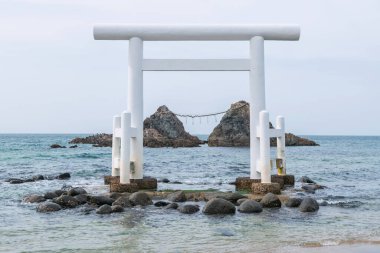 Itoshima, Fukuoka Bölgesi, Japonya 'daki Sakurai Futamigaura' da birkaç taş üzerinde beyaz bir torii kapısı. Ünlü seyahat yeri ya da turistik yerler.