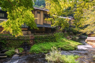 Japonya 'nın Kumamoto kentindeki Kurokawa kasabasında sonbaharda Şelale nehrinin kenarında Japon ryokan' ı. Kyushu 'daki cennet gibi sıcak bahar kasabasının ünlü seyahat yeri..