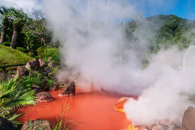 Chinoike Jigokuor Blood göleti. Mavi gökyüzü, Beppu, Oita, Japonya 'ya karşı ağır beyaz buharlı. İşte sıcak kırmızı su göleti ve sekiz cehennemin ünlü fotojeniği.