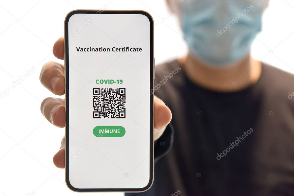 Digital certificate of vaccination against Covid-19. Man with face mask holding mobile phone with digital certificate of vaccination against Covid-19, a negative PCR test or recovery from coronavirus.
