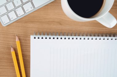 Office desk table with computer, supplies, blank notepad and coffee cup. Top view with copy space.