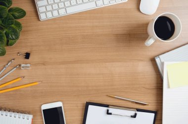 Office desk table with computer, smartphone, supplies, flower and coffee cup