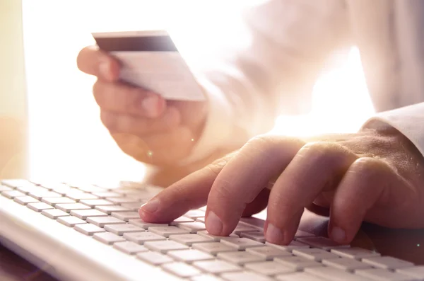 Primer plano de las manos del hombre sosteniendo la tarjeta de crédito y utilizando el teclado de la computadora —  Fotos de Stock