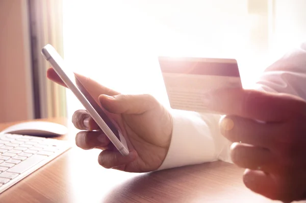 Primer plano de las manos del hombre sosteniendo tarjetas de crédito y utilizando el teléfono móvil — Foto de Stock