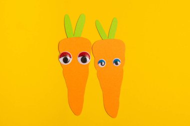 Sarı arka planda gözleri olan iki sevimli havuç. Canlı arkaplanda iki renkli havuç