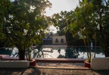 CUERNAVACA, MORELOS, MEKSİKO- 20 Şubat 2026: Cuernavaca, Morelos 'taki Jardin Borda' daki tarihi yapay göl ve yansıtıcı gölet manzarası. Bereketli palmiye ağaçları ve tropikal bitki örtüsüyle çevrelenmiş sakin su, çevreleyen yeşili yansıtır.