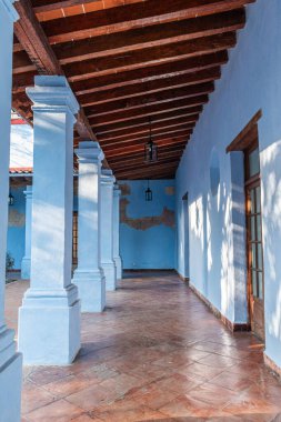 CUERNAVACA, MORELOS, MEXICO - 20 Şubat 2026: Cuernavaca, Morelos 'taki tarihi Jardin Borda' da geleneksel bir sömürge tarzı koridora dikey bir perspektif. Görüntü canlı açık mavi duvarlar, eski dokular, büyük beyaz kare