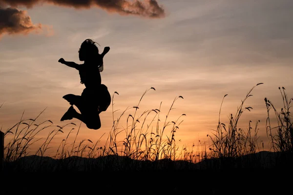 Silhouette of Child girl jumping over sunset background. Freedom and leisure vacation concept.