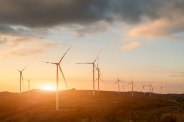 Rüzgar türbinlerinin silueti. Gün batımında dağ tepesinde rüzgar jeneratörlerinin güzel manzarası..
