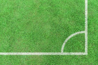 Yeşil çimenli bir futbol sahasında beyaz çizgili köşe işaretleri. Üst görünüm spor arka planı.