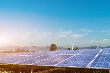 Güneş panelleri ve rüzgar türbinleri günbatımı arka planında elektrik üretiyor. Gelecekteki enerji çevre kavramı.