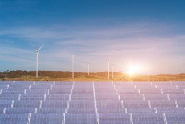 Mavi gökyüzü arka planında rüzgar türbinleri olan güneş panelleri. Yenilenebilir yeşil enerji kavramı dosttur.
