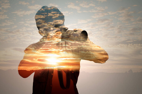 Double exposure of man taking photos and sunset sky.