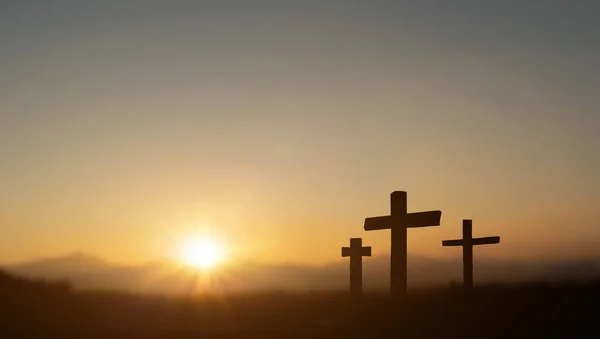 Crucifixion of jesus christ at sunset sky. Silhouette of three christian cross on blurred hill background.