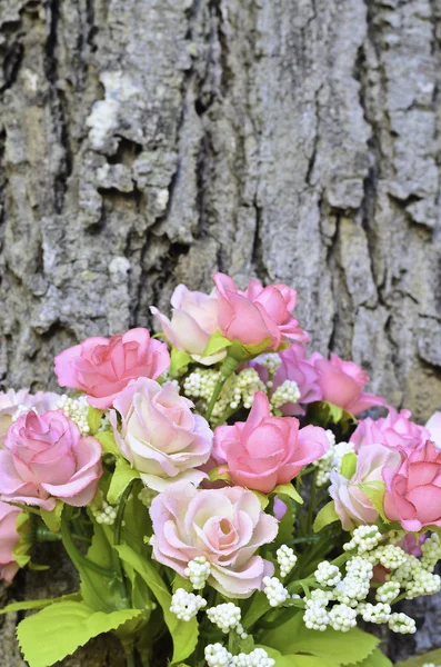 Rosa konstgjord ros bukett med träd bålen bakgrund — Stockfoto