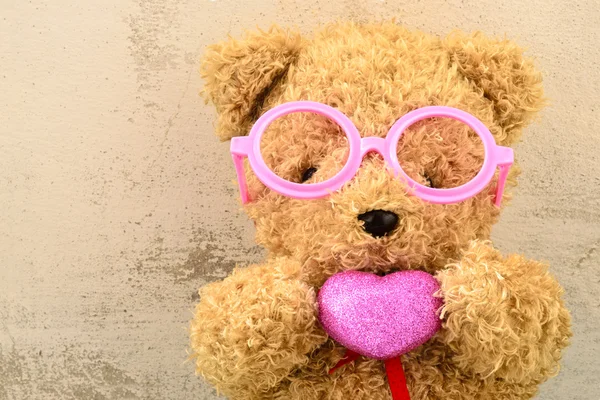 Liebe ly Bear Puppe trägt rosa Brille und hält rosa Herz sh — Stockfoto