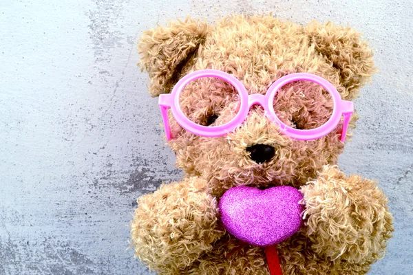 Love ly bear doll wearing pink glasses and holding pink heart sh — Stock Photo, Image