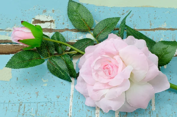 Artificial pink roses on grungy light blue wooden background — Stock Photo, Image