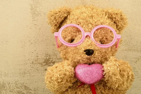 愛 ly クマのぬいぐるみピンクのメガネを身に着けていると sh ピンクのハートを保持しています。 — ストック写真