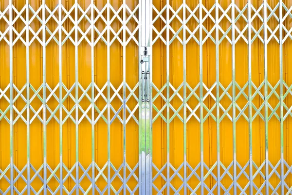 Yellow metal grille sliding door with pad lock and aluminum hand — Stock Photo, Image