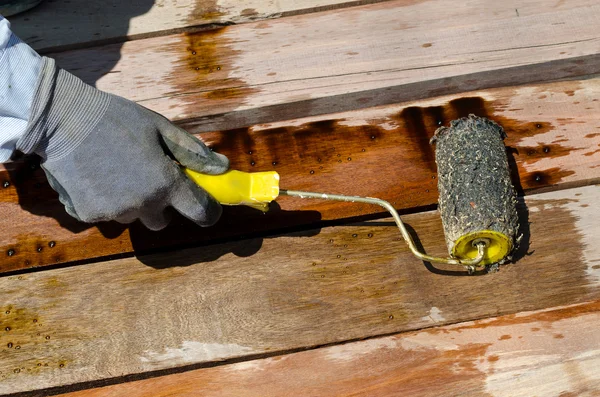 Trabalhador mão segurando pintura escova na textura de madeira — Fotografia de Stock