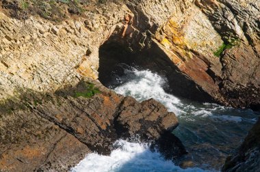 Bir okyanus dalgası Kaliforniya sahilindeki bir deniz kenarı mağarasının duvarlarına çarpıyor..