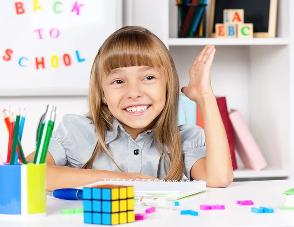 Kleines Mädchen sitzt am Schreibtisch im Klassenzimmer — Stockfoto