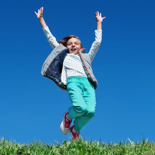 Lycklig liten flicka hoppa på ängen — Stockfoto