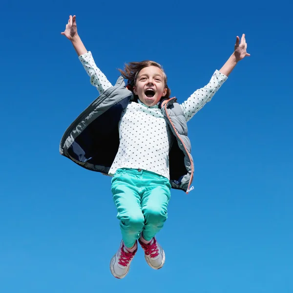 Glückliches kleines Mädchen springt gegen klaren Himmel — Stockfoto