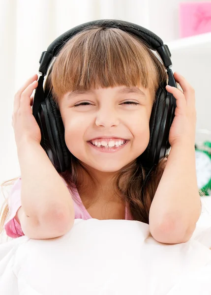 Menina na cama com fones de ouvido — Fotografia de Stock