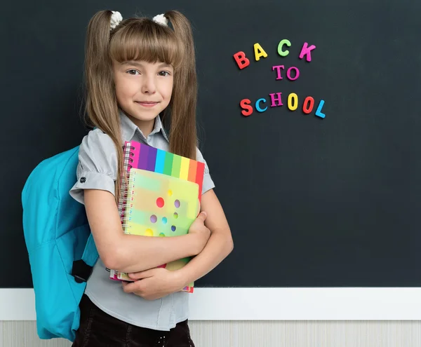 Girl with books at the chalkboard — Stock Photo, Image