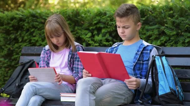 Мальчик и девочка читают книгу — стоковое видео