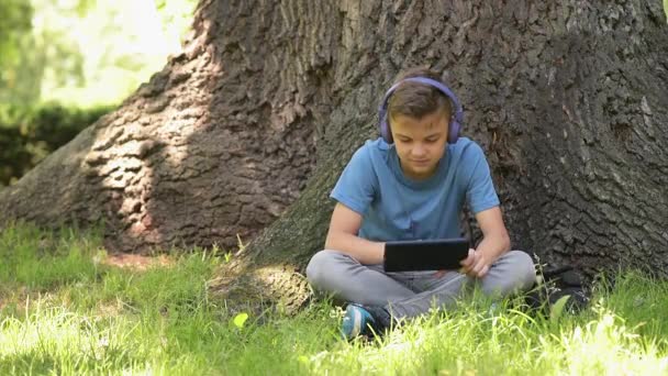 Хлопчик з планшетом у парку — стокове відео