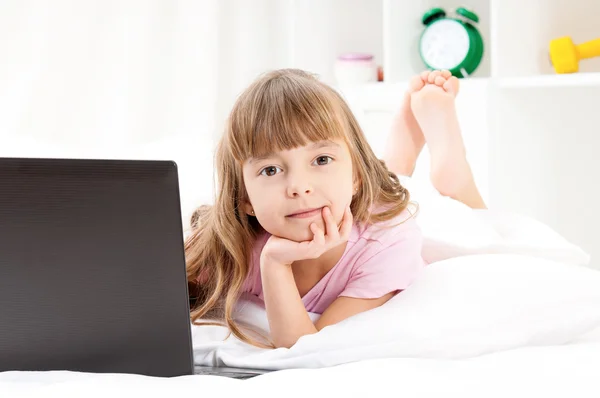 Ragazza con computer portatile sul letto — Foto Stock