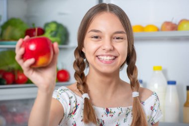 Buzdolabının yanında yemeği olan kız.