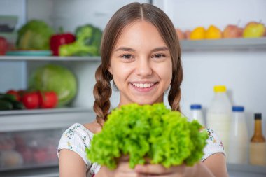 Buzdolabının yanında yemeği olan kız.
