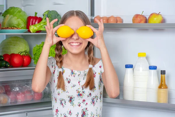 Девушка с едой возле холодильника Лицензионные Стоковые Изображения