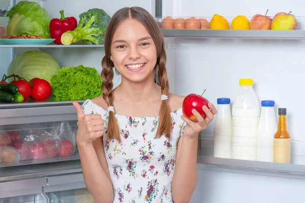 Chica con comida cerca de nevera Fotos de stock