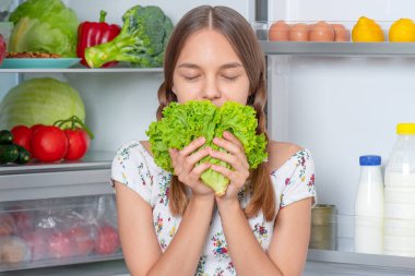 Buzdolabının yanında yemeği olan kız.