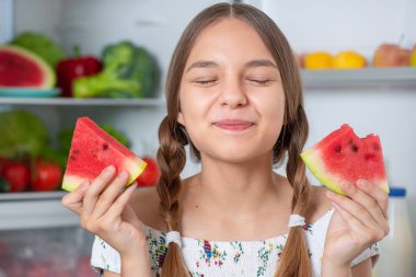 Buzdolabının yanında yemeği olan kız.