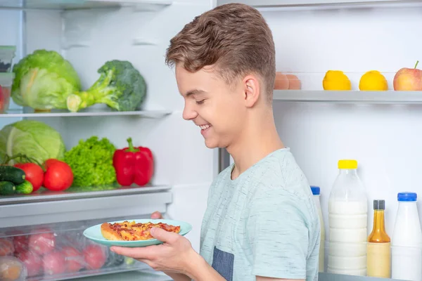 Хлопчик з їжею біля холодильника Ліцензійні Стокові Зображення
