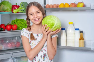 Buzdolabının yanında yemeği olan kız.