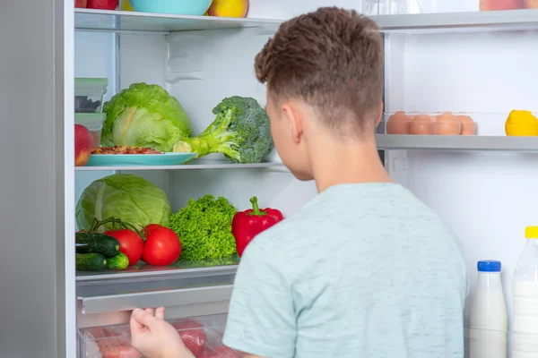 Menino com comida perto da geladeira — Fotografia de Stock