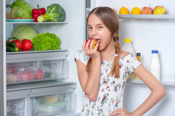 Κορίτσι με φαγητό κοντά στο ψυγείο Εικόνα Αρχείου