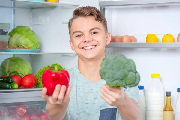 Menino com comida perto da geladeira — Fotografia de Stock