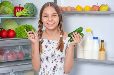 Buzdolabının yanında yemeği olan kız.