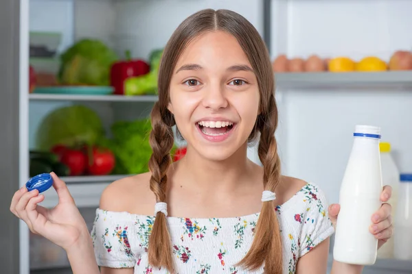 Meisje met eten in de buurt koelkast Stockfoto