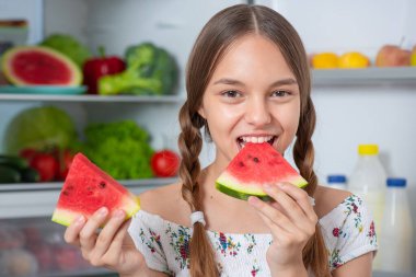 Buzdolabının yanında yemeği olan kız.