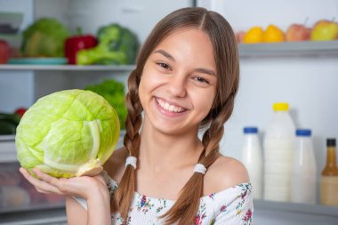 Buzdolabının yanında yemeği olan kız.